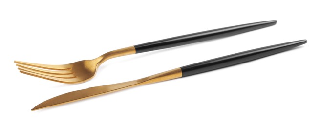 Photo of New golden fork and knife with black handles on white background