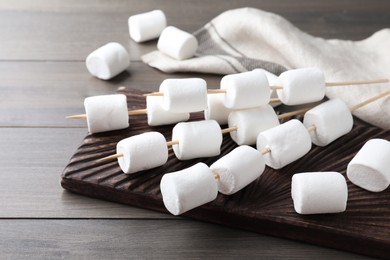 Sticks with sweet marshmallows on wooden table