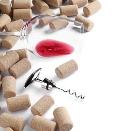 Photo of Corkscrew, glass with red wine and stoppers on white background
