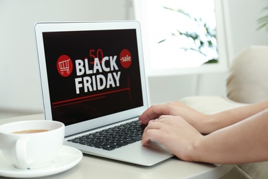 Woman using laptop with Black Friday announcement on screen at table, closeup