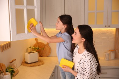 Mother and daughter cleaning up kitchen together at home