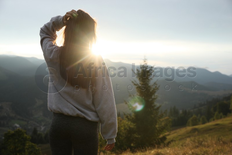 Photo of Beautiful young woman enjoying her time in mountains, back view. Space for text