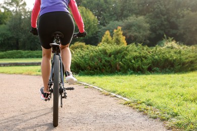 Photo of Woman riding bicycle on road outdoors, back view. Space for text