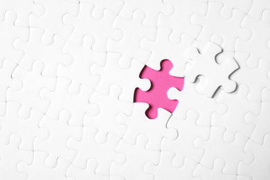 Blank white puzzle with separated piece on pink background, top view. Space for text