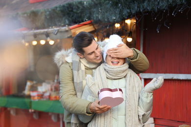 Man presenting Christmas gift to his girlfriend at winter fair
