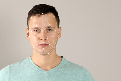 Facial recognition system. Young man with biometric identification scanning grid on beige background, space for text