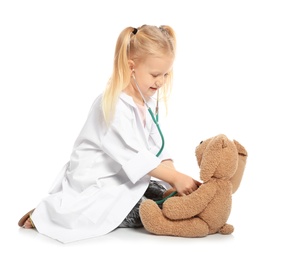 Cute child imagining herself as doctor while playing with stethoscope and toy bunny on white background