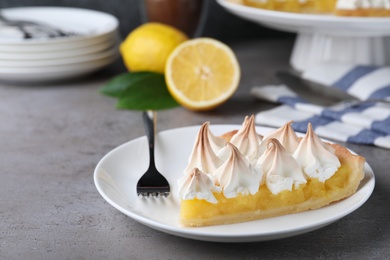Piece of delicious lemon meringue pie served on grey table. Space for text