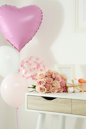 Photo of Beautiful bouquet of roses, gifts and balloons on white table. Happy birthday greetings