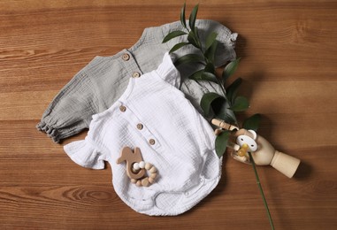 Flat lay composition with children's clothes, toys and pacifier on wooden table