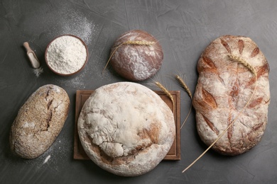 Different kinds of fresh bread on grey table, flat lay