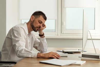 Photo of Sleepy man snoozing at workplace in office