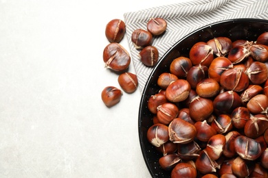 Delicious roasted edible chestnuts on light grey table, flat lay. Space for text