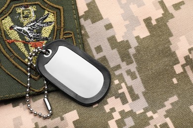 Military ID tag and patch on pixel Ukrainian camouflage, top view. Space for text