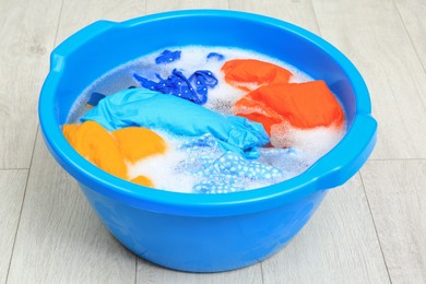 Basin with colorful clothes on floor. Hand washing laundry
