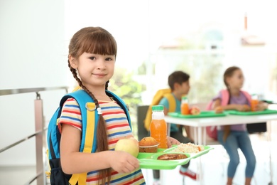 Girl holding tray with healthy food at school canteen