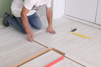 Photo of Man installing new laminate flooring indoors, closeup