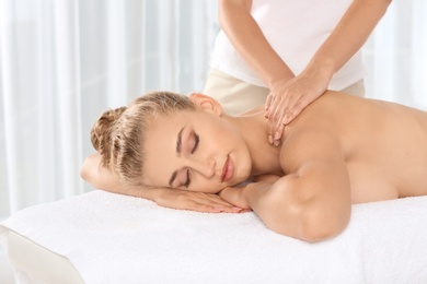 Photo of Relaxed woman receiving neck massage in wellness center