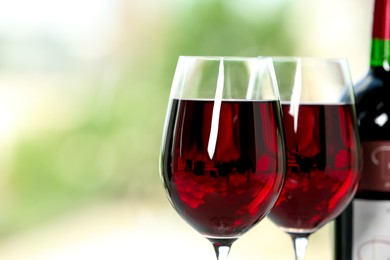 Photo of Glasses of delicious red wine on blurred background, closeup. Space for text