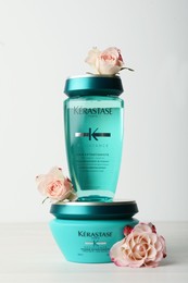 MYKOLAIV, UKRAINE - SEPTEMBER 07, 2021: Kerastase hair care cosmetic products and beautiful flowers on white wooden table