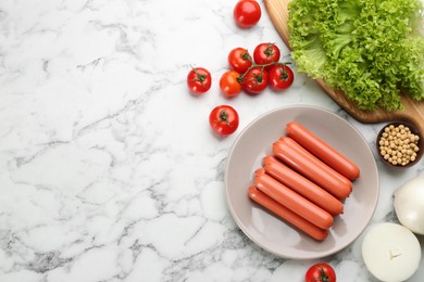 Fresh raw vegetarian sausages, soybeans and vegetables on white marble table, flat lay. Space for text