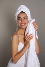 Beautiful young woman with towels on grey background