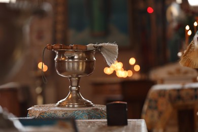 Silver vessel with holy water and brush on stand in church. Baptism ceremony