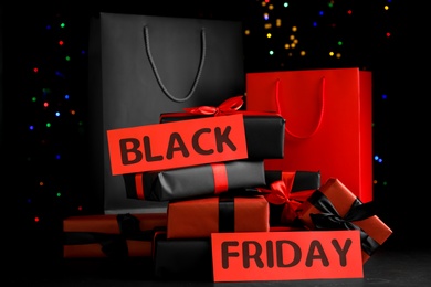 Paper shopping bags and gift boxes against blurred lights. Black Friday sale