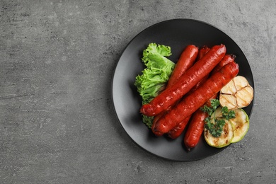 Delicious grilled sausages and vegetables on grey table, top view. Space for text