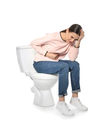 Young woman suffering from digestive disorder on toilet bowl, white background