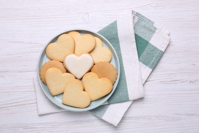 Heart shaped cookies and napkin on white wooden table, flat lay