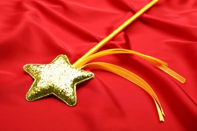Beautiful golden magic wand on red fabric, closeup