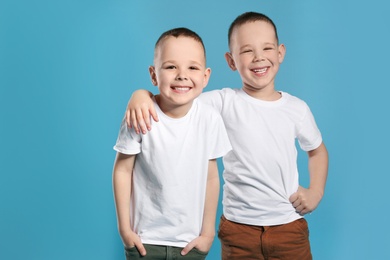 Portrait of cute twin brothers on color background