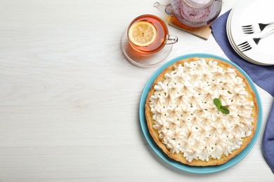 Flat lay composition with delicious lemon meringue pie on white wooden table, space for text