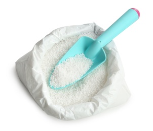 Bag with granular mineral fertilizer and scoop on white background, top view