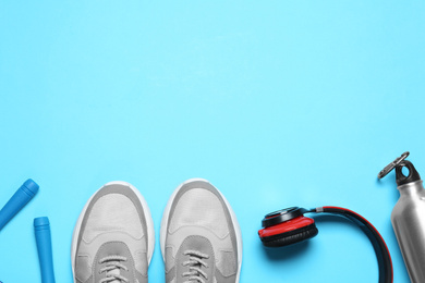 Flat lay composition with man's sneakers and fitness items on light blue background, space for text