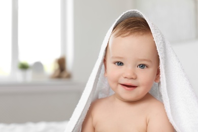 Adorable little baby with white towel indoors
