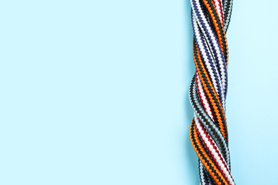Top view of twisted colorful ropes on light blue background, space for text. Unity concept