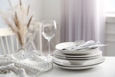 Set of clean dishware, wineglasses and cutlery on white table indoors