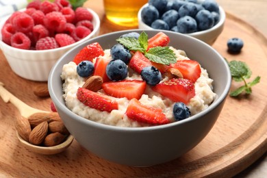 Tasty oatmeal porridge with berries and almond nuts served on wooden board
