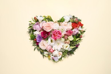 Beautiful heart made of different flowers on beige background, top view