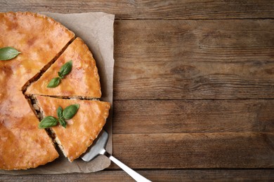 Delicious pie with meat and basil on wooden table, top view. Space for text
