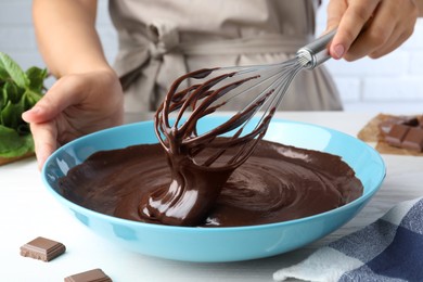 Photo of Woman making delicious chocolate cream at white wooden table, closeup