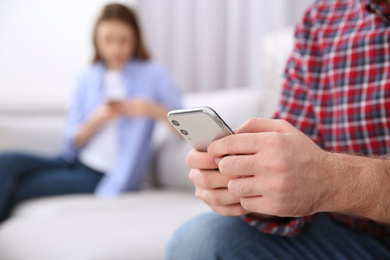Man with smartphone ignoring his girlfriend at home, closeup. Relationship problems