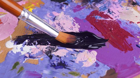 Photo of Artist's palette with mixed paints and brush, closeup