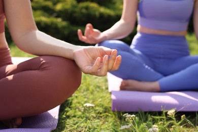 Women practicing yoga on mats outdoors, closeup