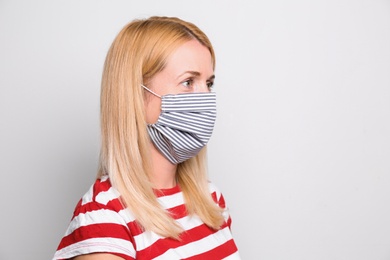 Woman wearing handmade cloth mask on white background, space for text. Personal protective equipment during COVID-19 pandemic