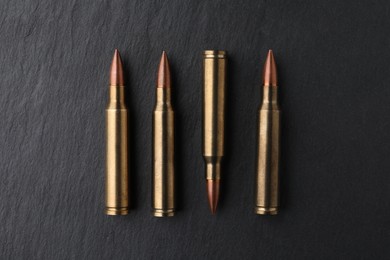 Many bullets on black table, flat lay. Military ammunition