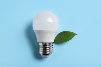Light bulb and green leaf on color background, flat lay