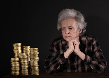 Image of Pension plan. Senior woman and stacks of coins on black background